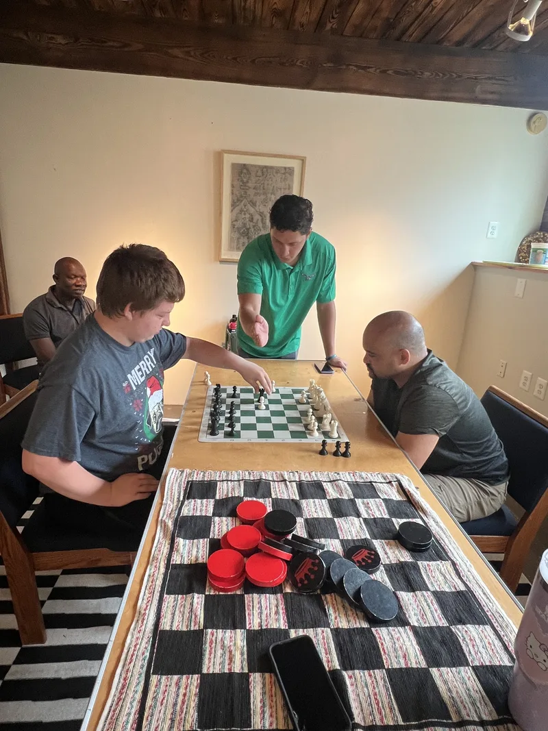 Members study the board mid-match at Chess and Checkers Club, with a giant checkers set close by